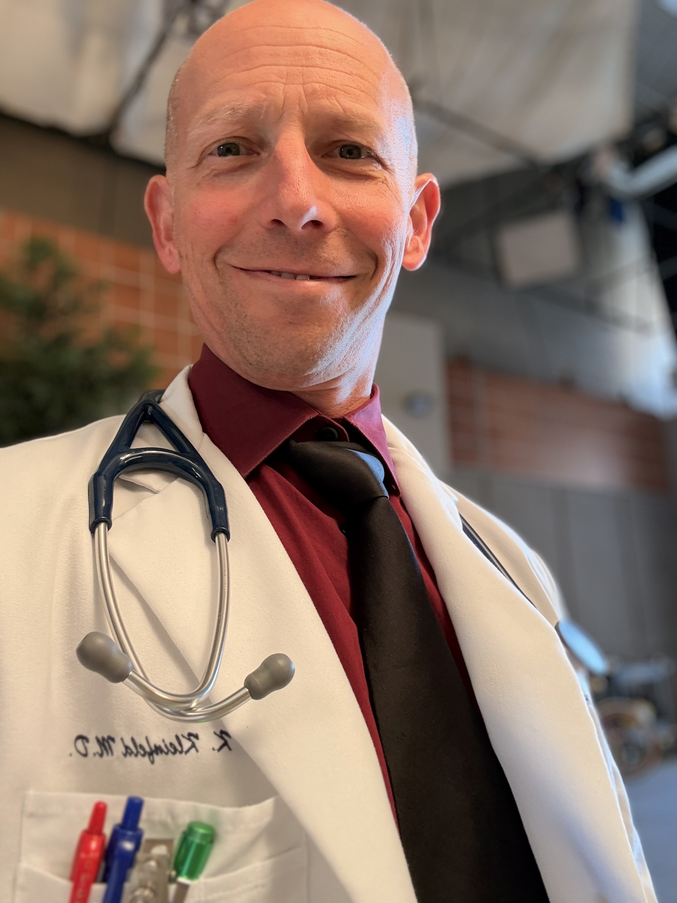 Randy Loveridge in a white doctor coat with a stethoscope on the set of Grey's Anatomy